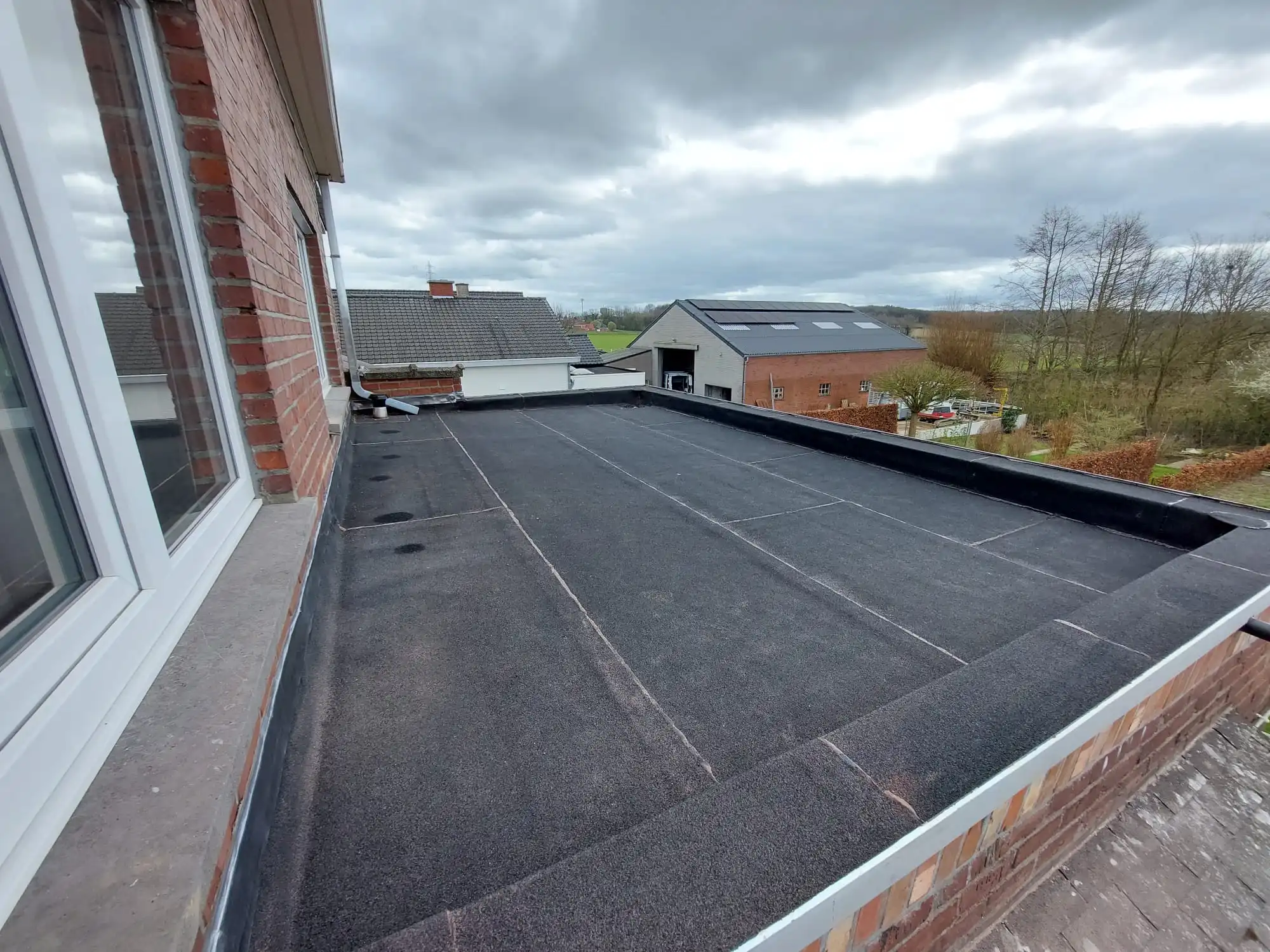 Een camionette met het logo van Dakwerken Desmet Branko voor een huis